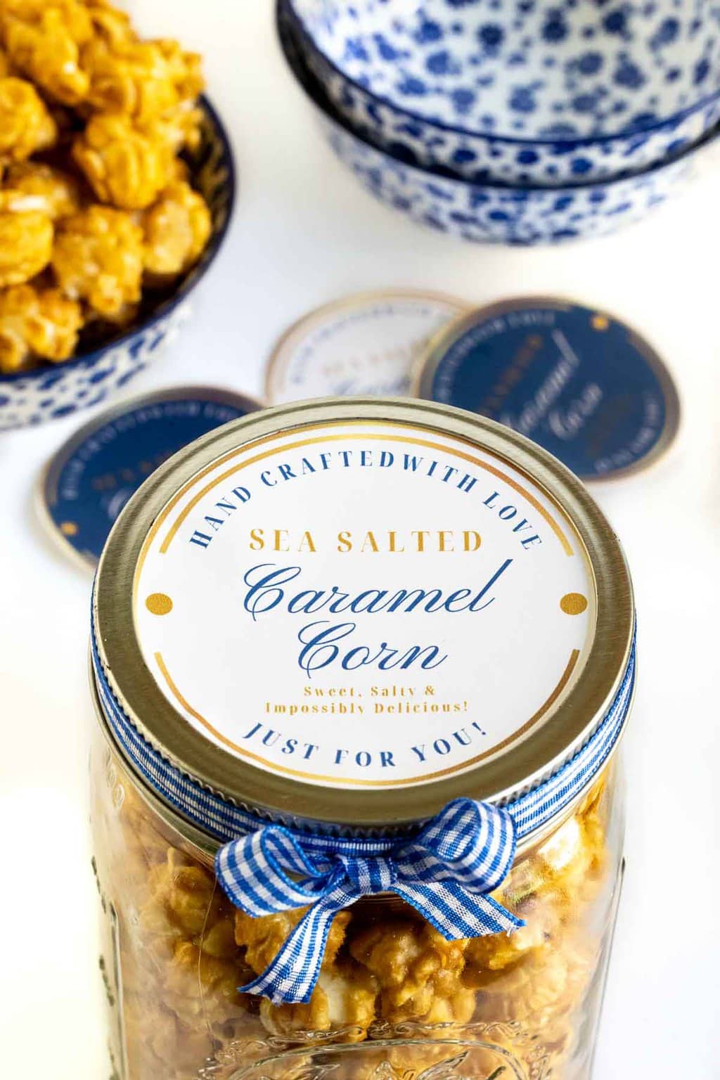 Vertical closeup photo of a custom Avery label for giving Ridiculously Easy Sea Salted Microwave Caramel Corn as gifts.