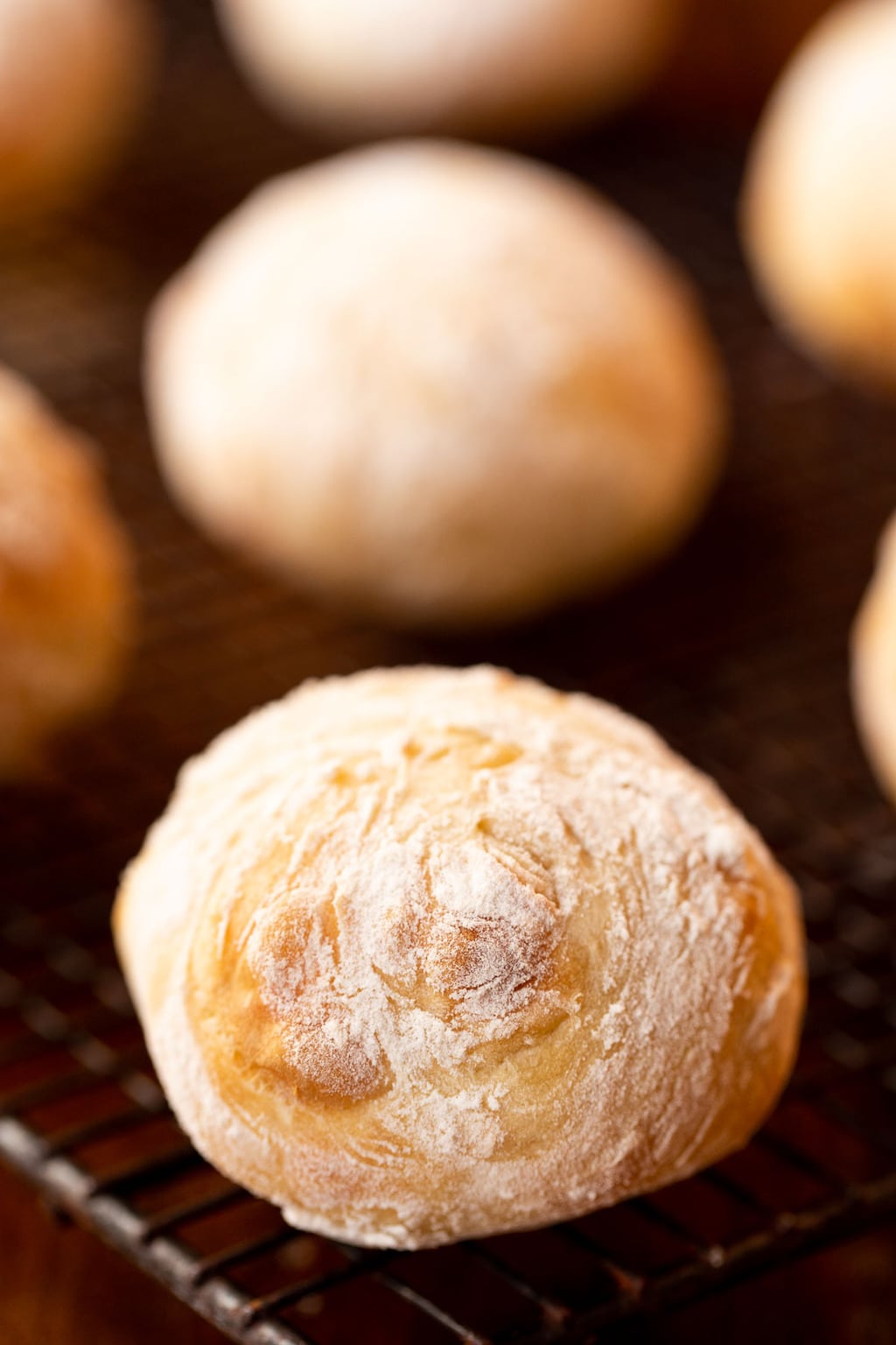 Vertical closeup photo of a batch of Ridiculously Easy Artisan Rolls on a cooling rack.