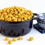 Horizontal photo of a dark blue cast iron Staub pot filled with Ridiculously Easy Sea Salted Microwave Caramel Corn