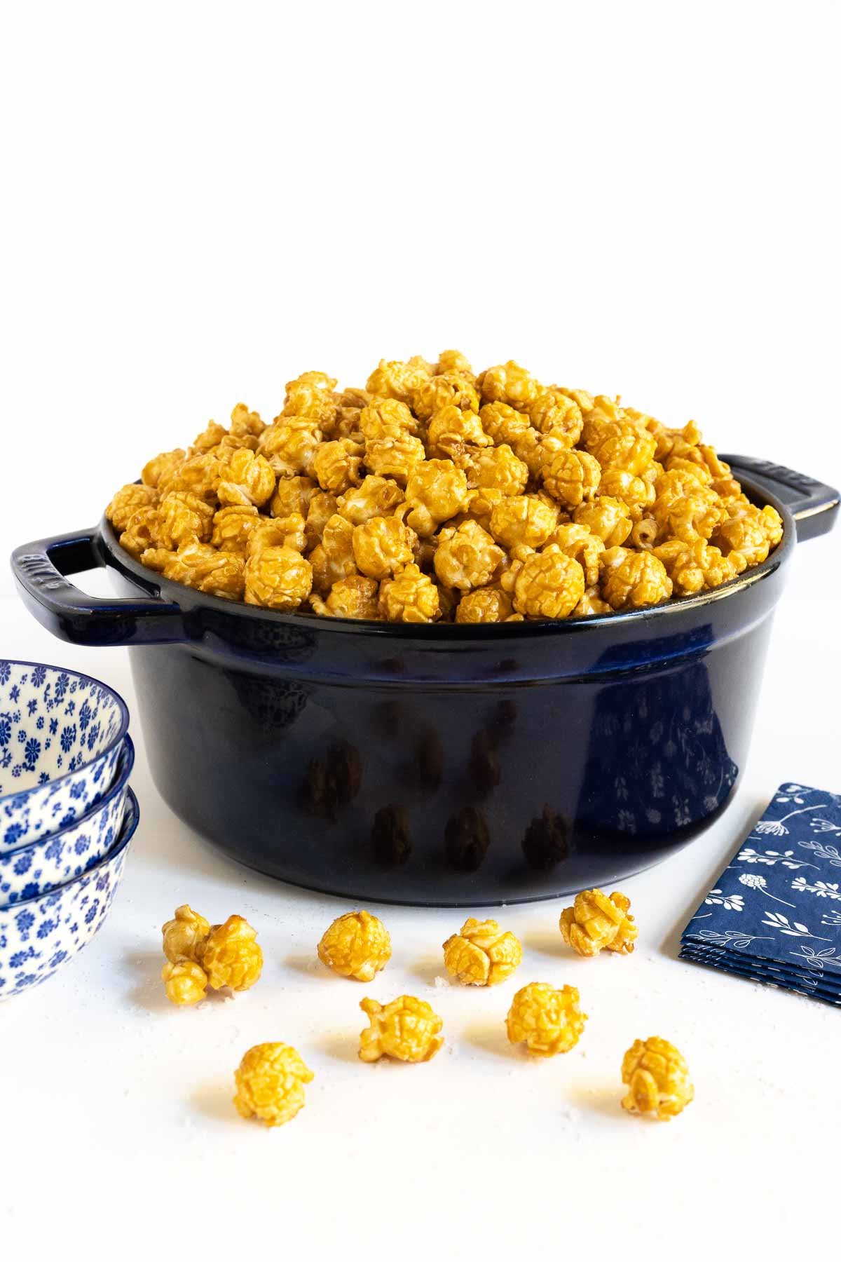 Vertical photo of a batch of Ridiculously Easy Sea Salted Microwave Caramel Corn in a dark blue Staub cast iron pot.