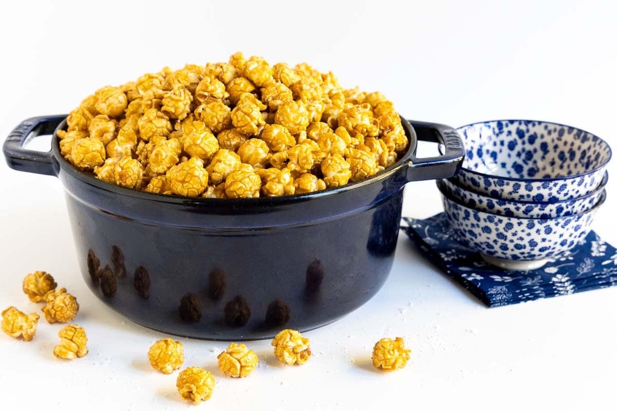 Horizontal photo of a dark blue Staub kettle filled with Ridiculously Easy Sea Salted Microwave Caramel Corn .