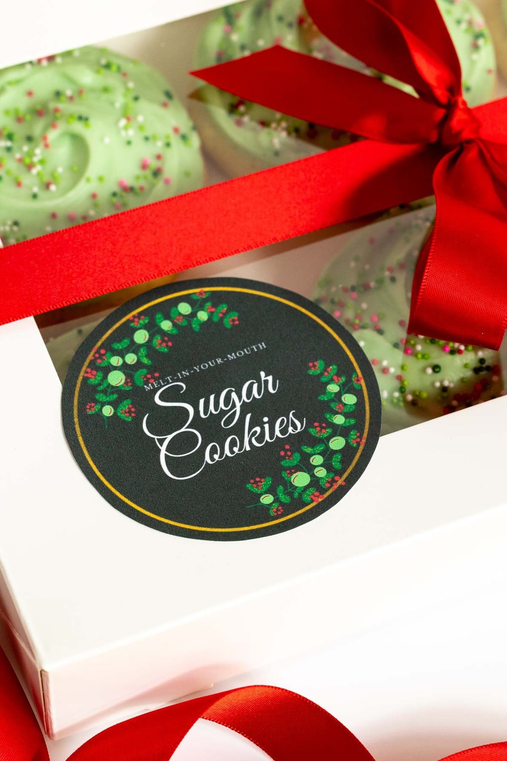 Extreme vertical closeup photo of a box of Copycat Crumbl Christmas Sugar Cookies ready for gift-giving with a custom label.