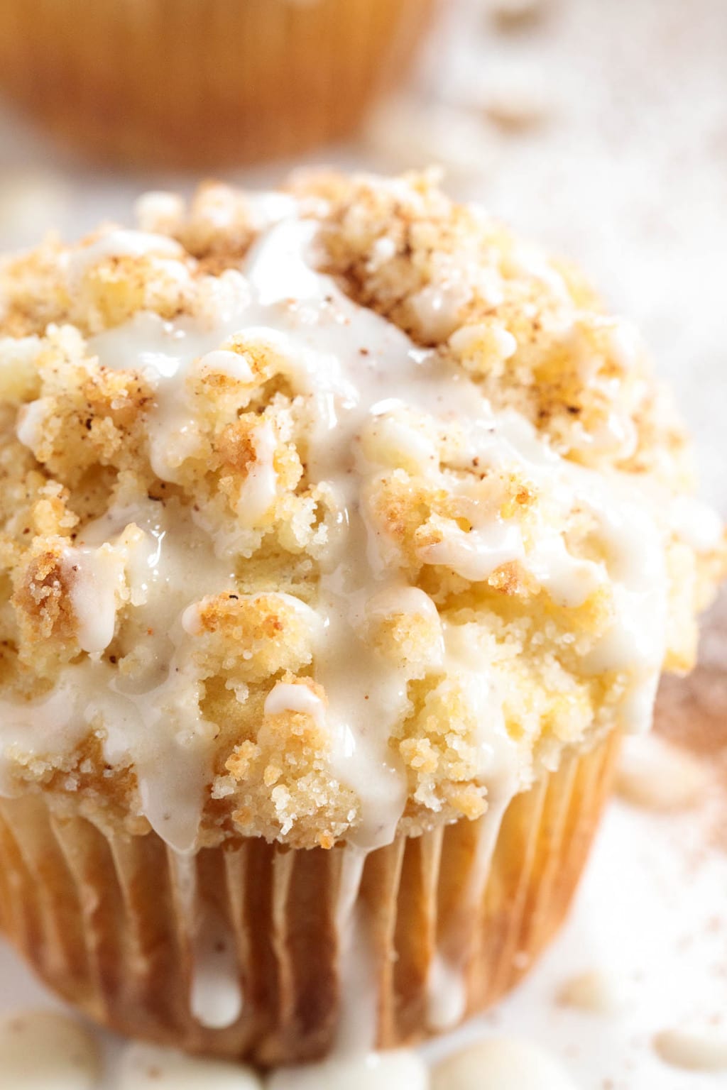 Vertical extreme closeup photo of a Eggnog Crumble Muffin on a white marble surface.