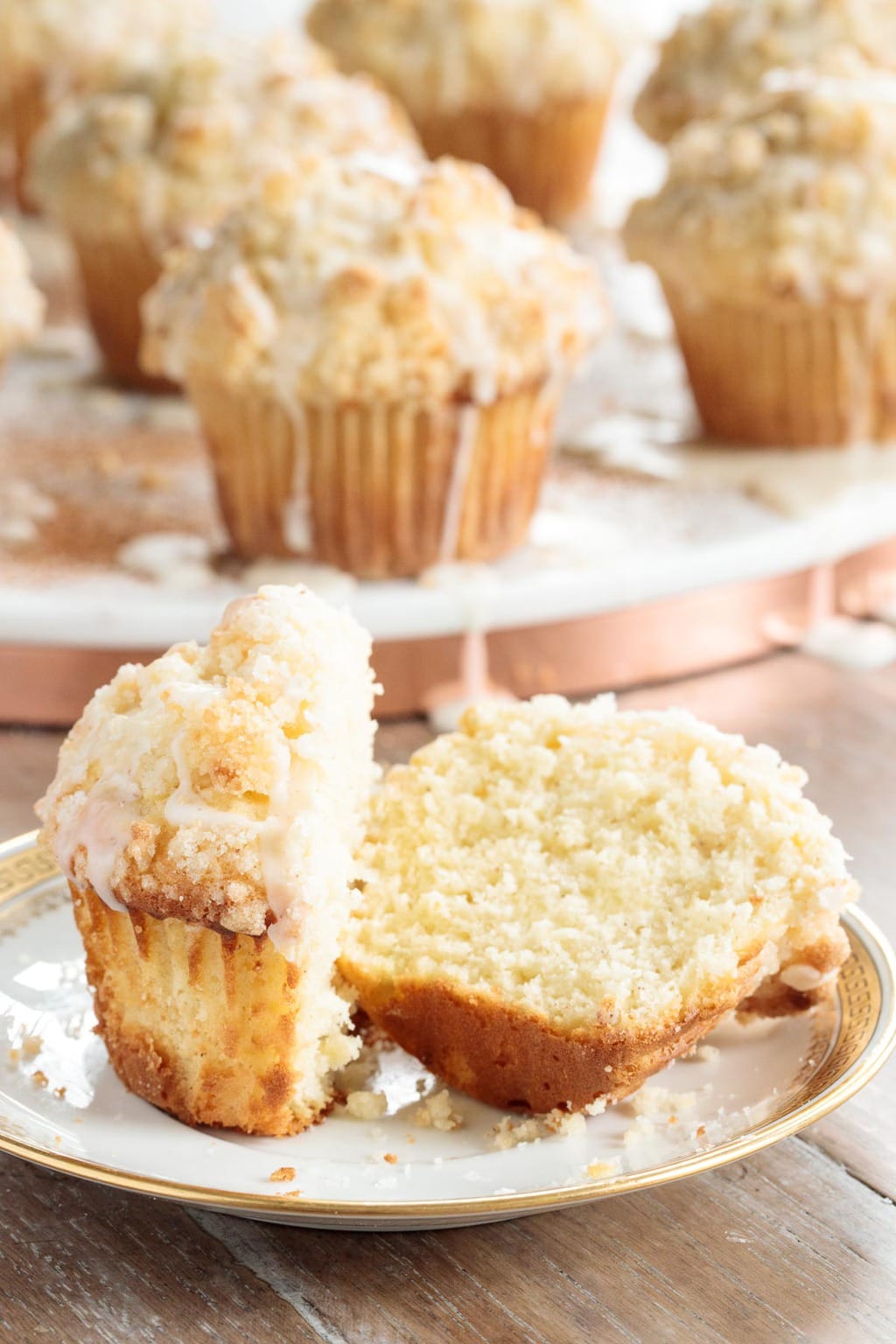 Vertical closeup photo of a batch of Eggnog Crumble Muffins with one sliced in half to display the crumb.