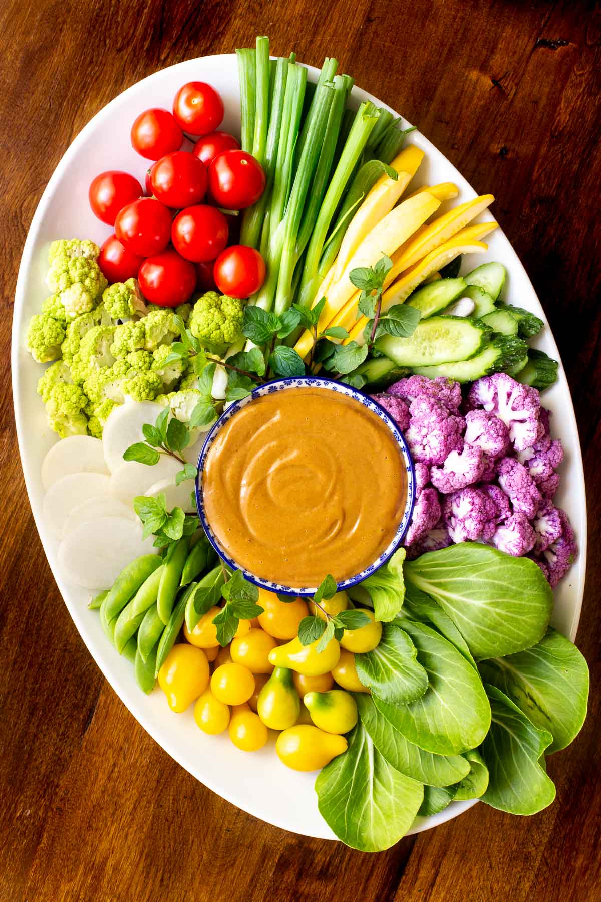Overhead vertical photo of an appetizer platter filled with fresh vegetables and featuring 5 Minute Easy Peanut Sauce in the center.