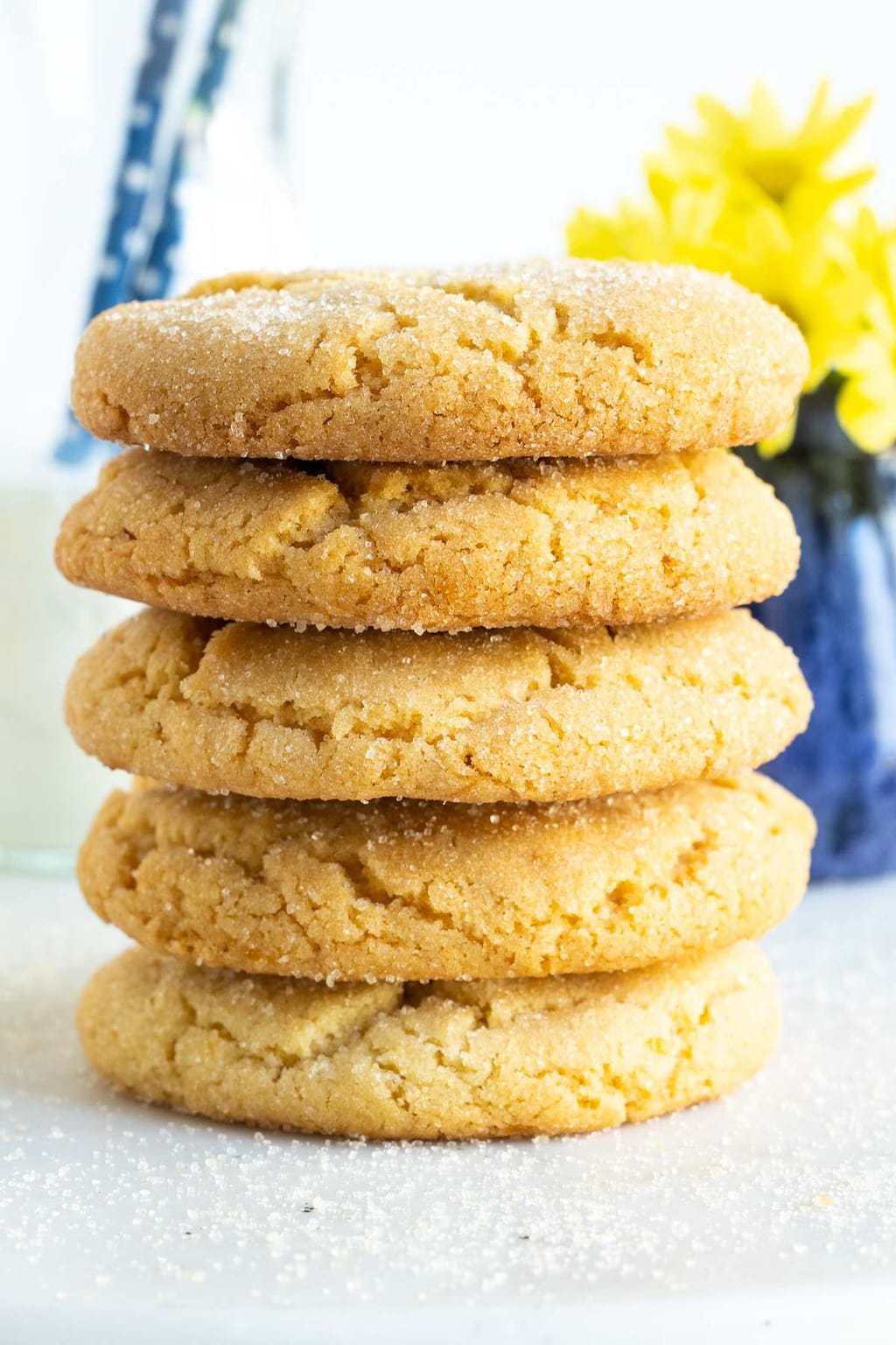 Vertical closeup photo of a stack of Crinkly Crackly Lemon Sugar Cookies on a white gloss surface.