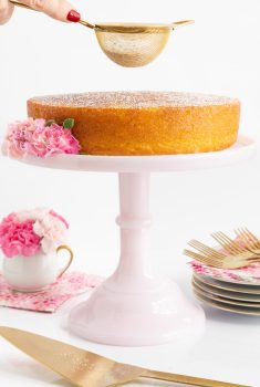 Vertical picture of Ridiculously Easy French Butter Cake on a white cake stand with flowers
