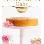 Vertical photo of a Ridiculously Easy French Butter Cake on a pink glass pedestal cake stand with a person sifting powdered sugar over the top of the cake.