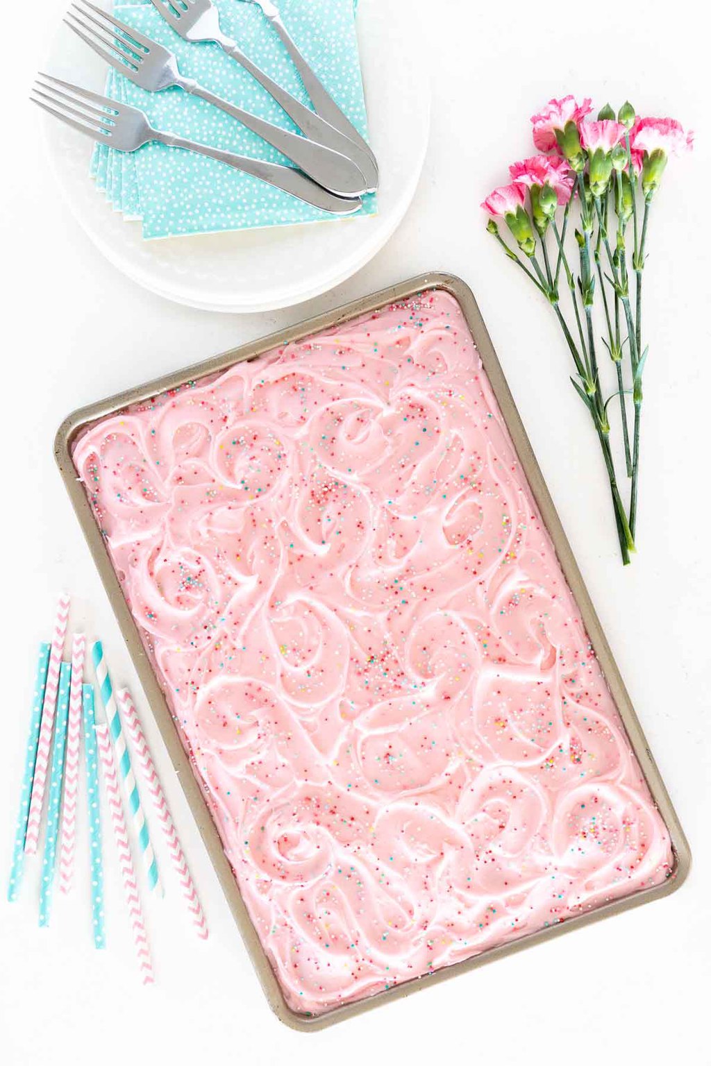 Overhead vertical photo of a Funfetti Sheet Cake with pink icing in a sheet pan .