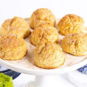 Horizontal photo of a batch of Ridiculously Easy Snickerdoodle Scones on a white pedestal plate.