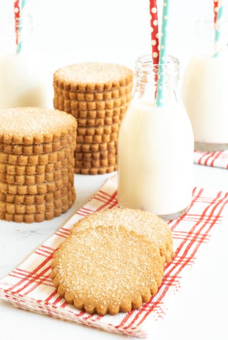 Vertical picture of Mexican Cinnamon Sugar Shortbread Cookies in stacks with glasses of milk