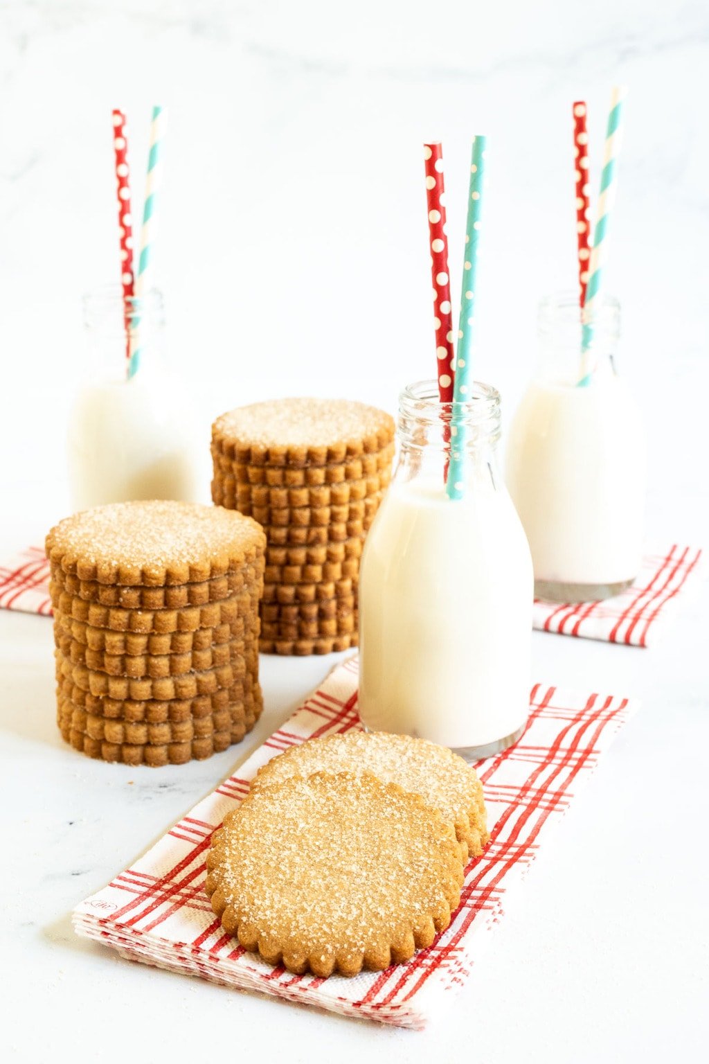 Vertical photo of a batch of Mexican Sugar Cinnamon Shortbread with small jars of milk.