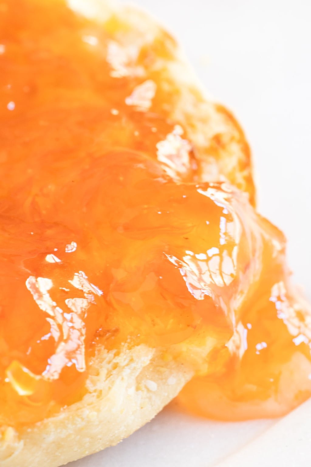 Vertical ultra closeup photo of Pink Grapefruit Marmalade spread on top of an English muffin.