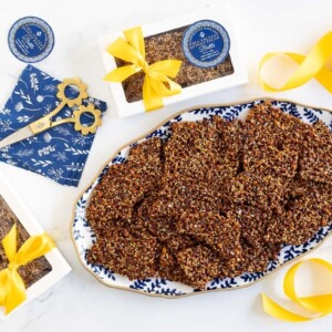 Horizontal overhead photo of a batch of Sea-Salted Quinoa Pecan Brittle with custom gift labels and decorative boxes.