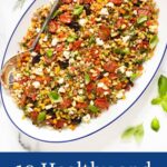 Vertical overhead photo of a Chopped Mediterranean Farro Salad on a white serving platter with blue trim.