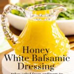 Vertical closeup photo of a cut glass jar filled with Honey White Balsamic Dressing with a black word text title at the bottom of the photo.