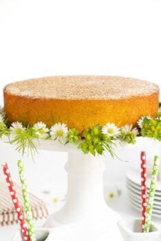 Vertical picture of Mexican Churro Cake on a white cake stand decorated with small flowers
