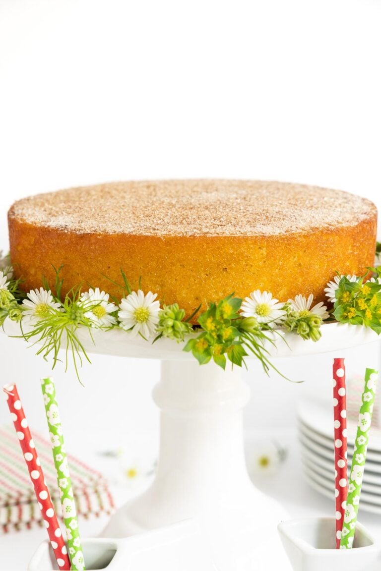 Vertical picture of Mexican Churro Cake on a white cake stand decorated with small flowers
