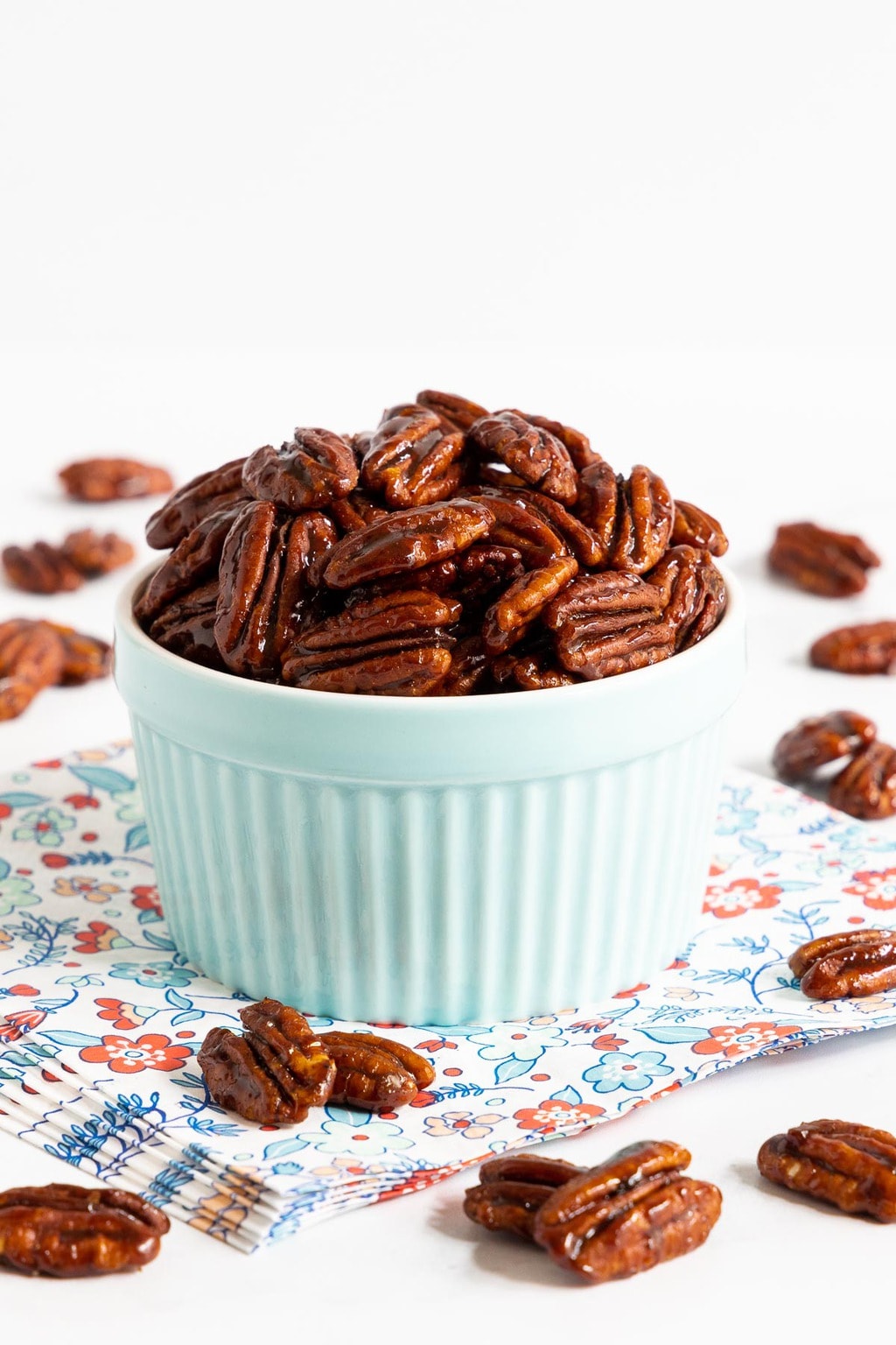 Vertical closeup photo of a batch of Southwest Sweet and Spicy Glazed Pecans in a pale blue ramekin.