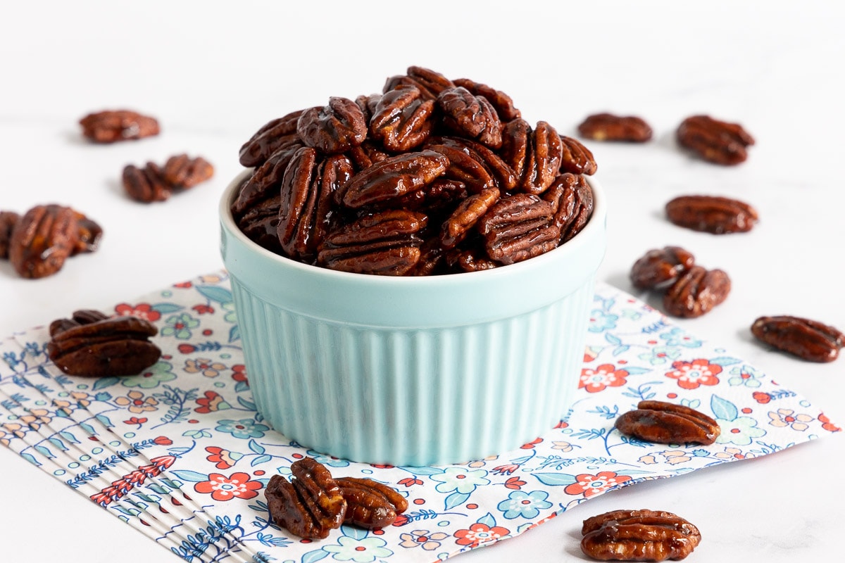 Horizontal photo of a batch of Southwest Sweet and Spicy Glazed Pecans in a pale blue ramekin bowl.