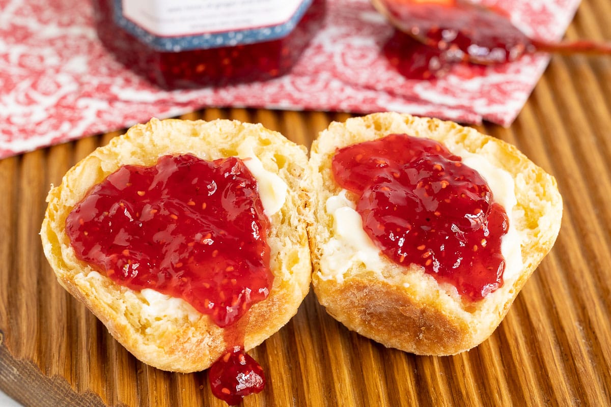 Vertical ultra closeup photo of homemade brioche buns spread with Strawberry Raspberry Lemongrass Jam and butter.
