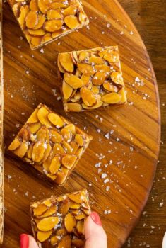 Horizontal overhead photo of a batch of Honey Caramel Almond Shortbread Bars on a round wood platter.
