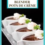 Vertical closeup photo of a row of Ridiculously Easy Blender Chocolate Pots de Crème in modern white ramekins garnished with whipped cream and fresh mint leaves.