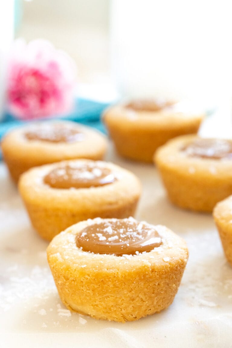 Salted Caramel Shortbread Bites with a blue napkin and pink flowers.