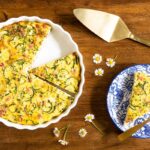 Horizontal overhead photo of a Southwestern Zucchini Ham Crustless Quiche on a round wood serving plate.