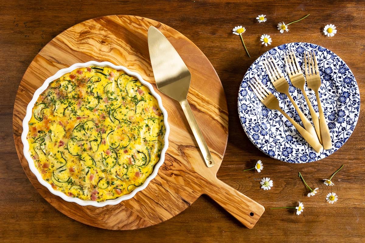 Horizontal overhead photo of a Southwestern Zucchini Ham Crustless Quiche on a round wood serving tray.