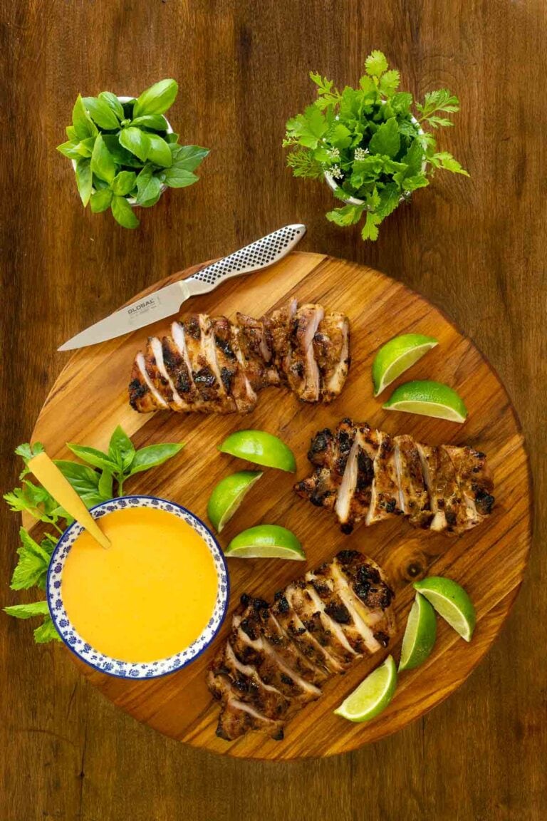Overhead picture of Grilled Chicken Thighs with Coconut Chili Lime Sauce on a wooden cutting board with fresh herbs