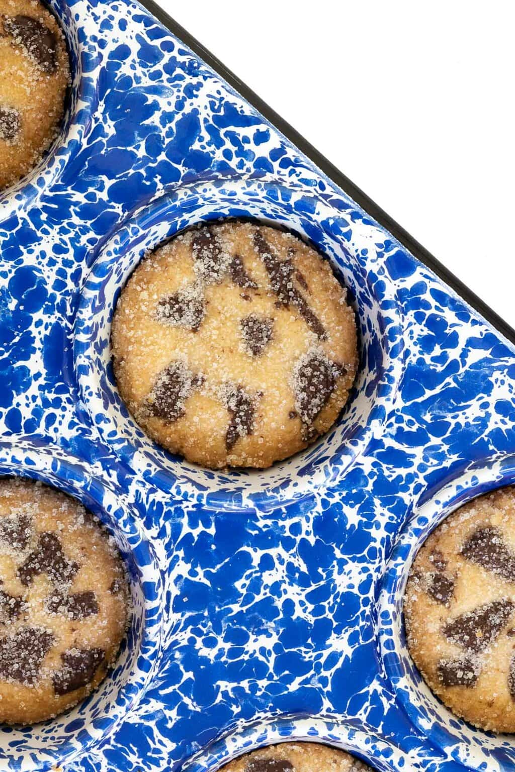 Vertical overhead closeup photo of a batch of Ridiculously Easy Peanut Butter Shortbread Cookies in a blue and white speckled muffin pan.