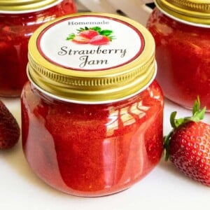 Horizontal closeup photo of a batch of Strawberry Jam in jars with custom labels for gift giving.