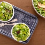 Horizontal overhead photo of two individual Classic French Bistro Salads on a wood table.