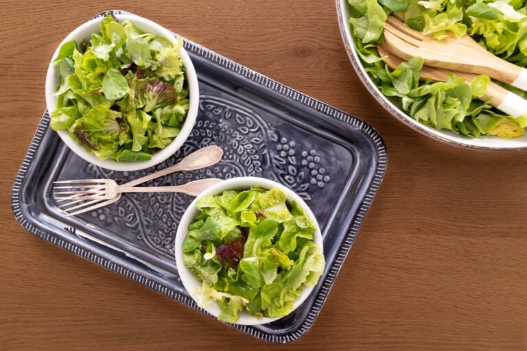 Horizontal overhead photo of two individual Classic French Bistro Salads on a wood table.