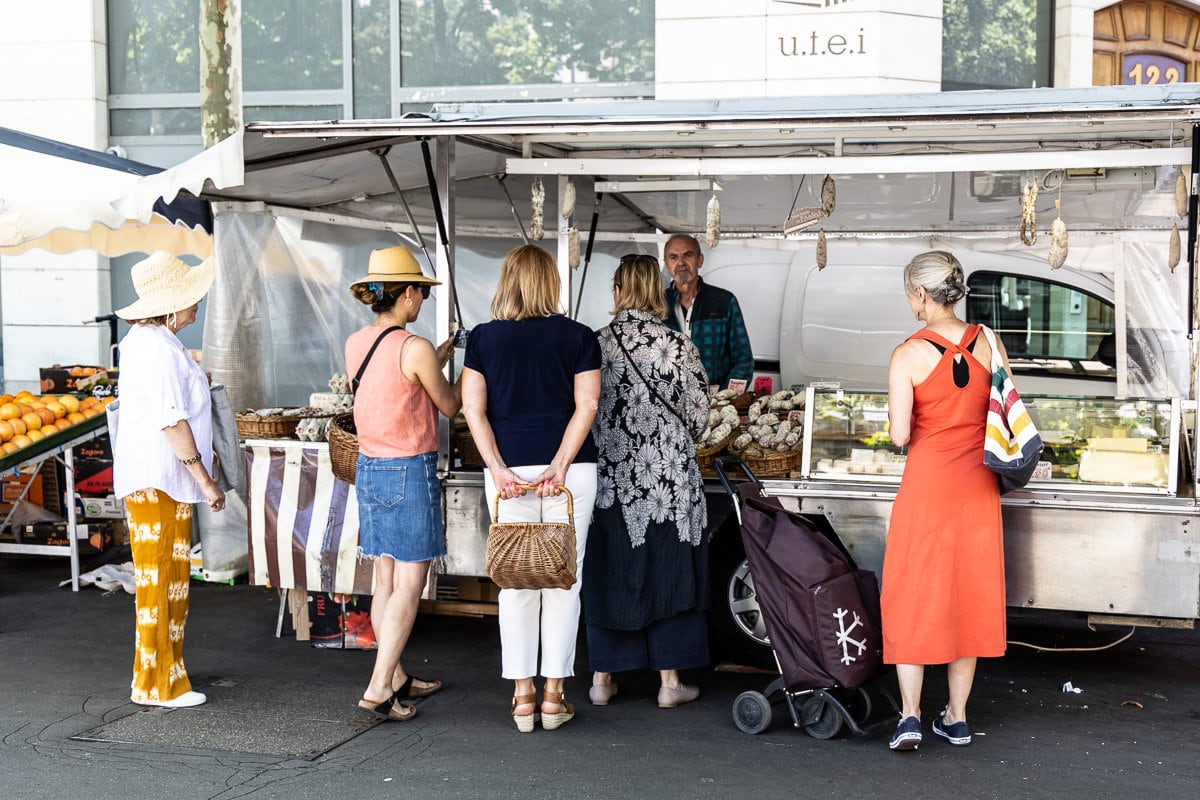 Horizontal photo of Lucy and her students from Plum Lyon cooking school at the French market in Lyon, France.
