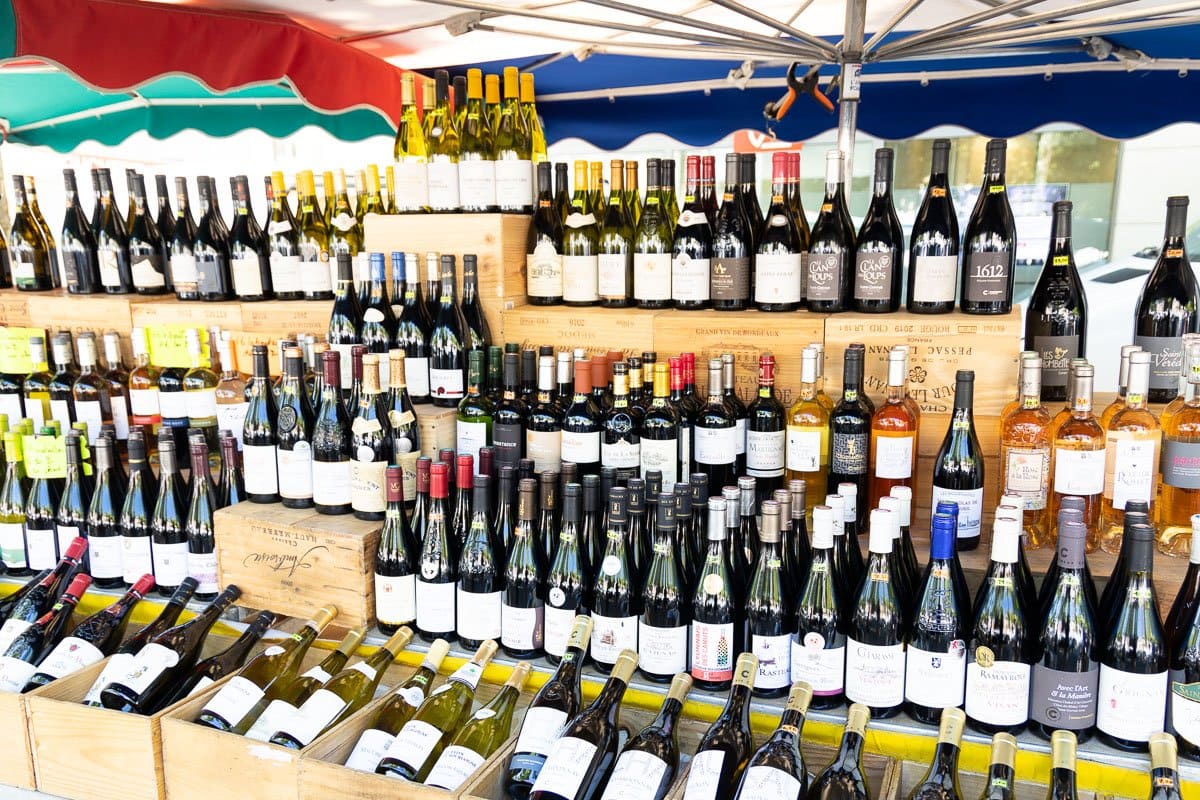 Horizontal photo of a wall of bottles of French wines at the French market in Lyon, France.