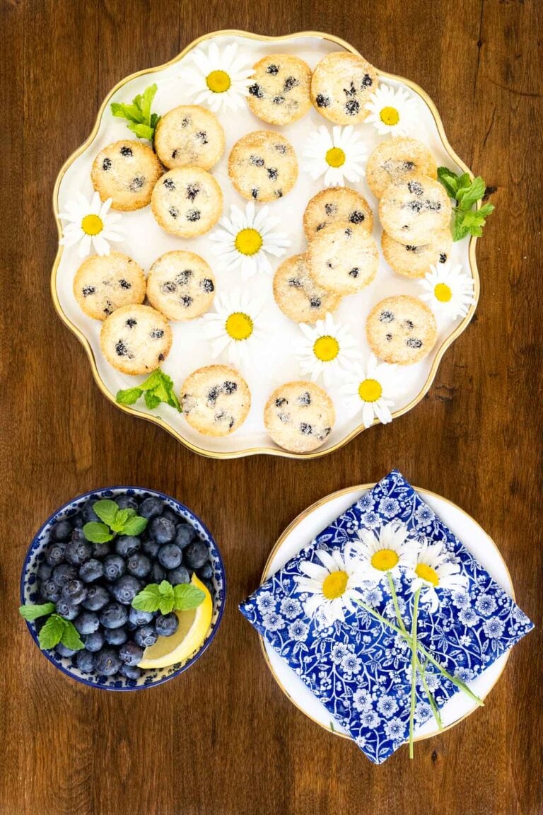 Lemon Blueberry Shortbread Bites on a white platter with blue and white napkins and a bowl of blueberries. 