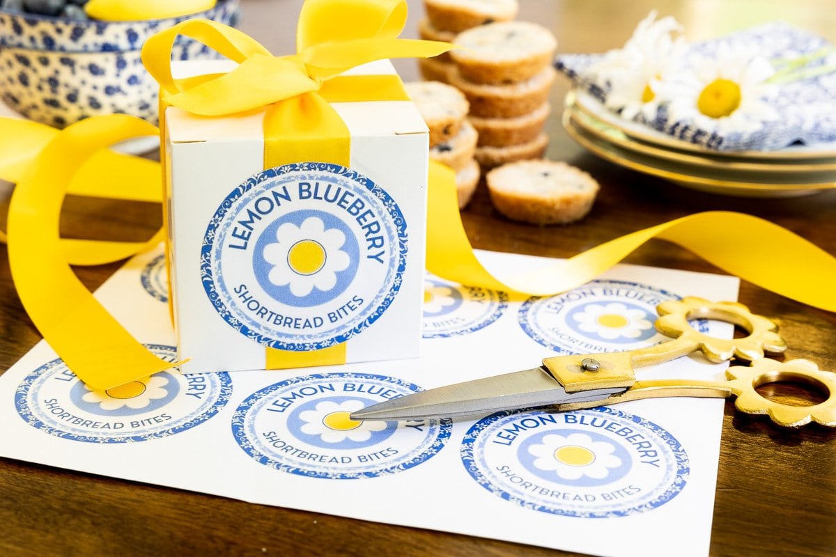 Horizontal photo of custom Ridiculously Easy Lemon Blueberry Shortbread Bite labels and boxes for gift giving.