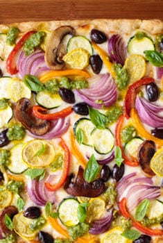 Horizontal overhead photo of a Ridiculously Easy Roasted Veggie Sheet Pan Pizza on a wood cutting board.