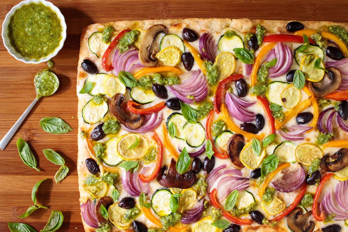 Overhead horizontal photo of a Roasted Veggie Sheet Pan Pizza on a wood table.