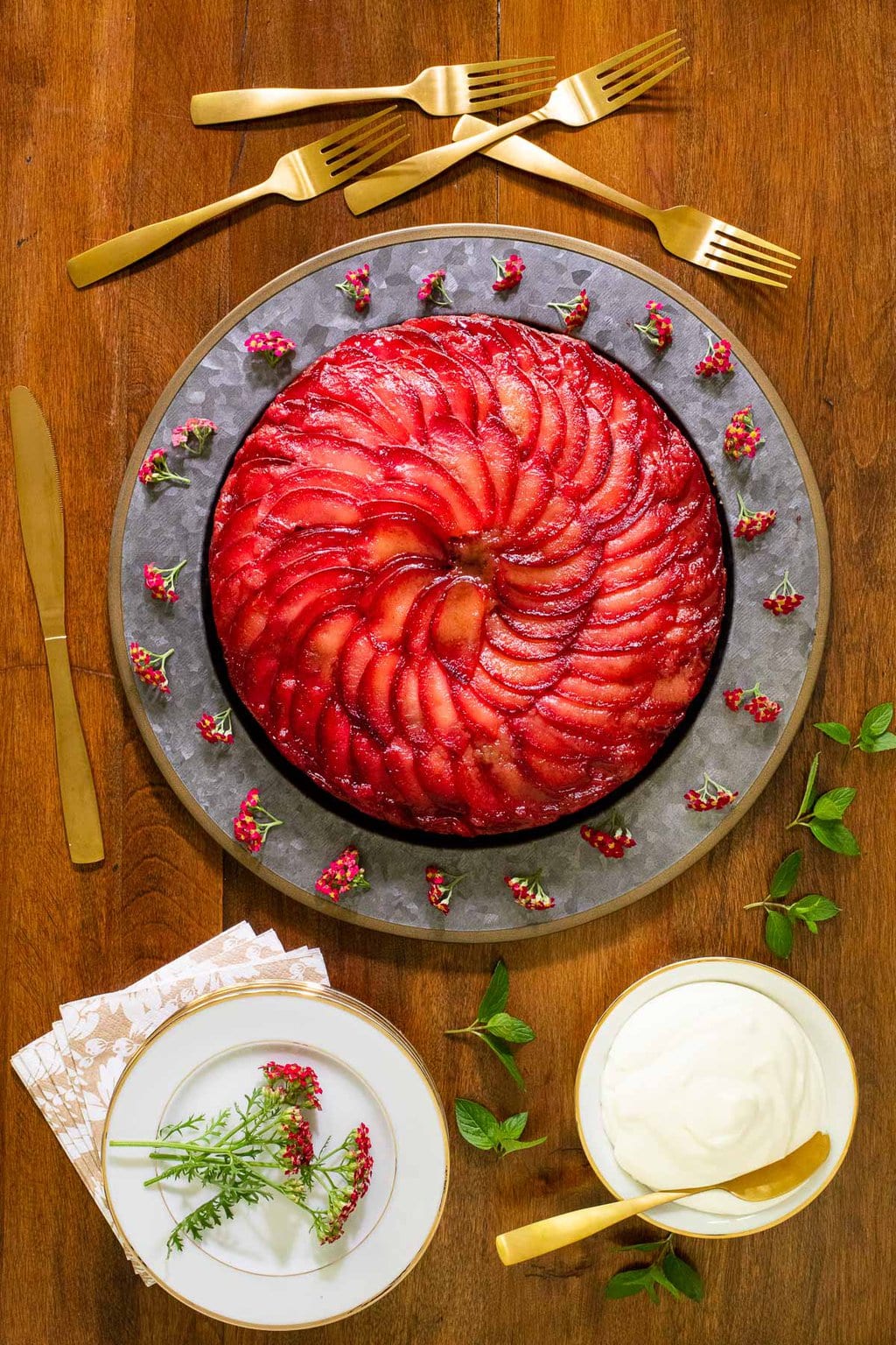 Vertical overhead photo of a Upside Down Plum Yogurt Cake on a galvanized cake plate on a wood table.