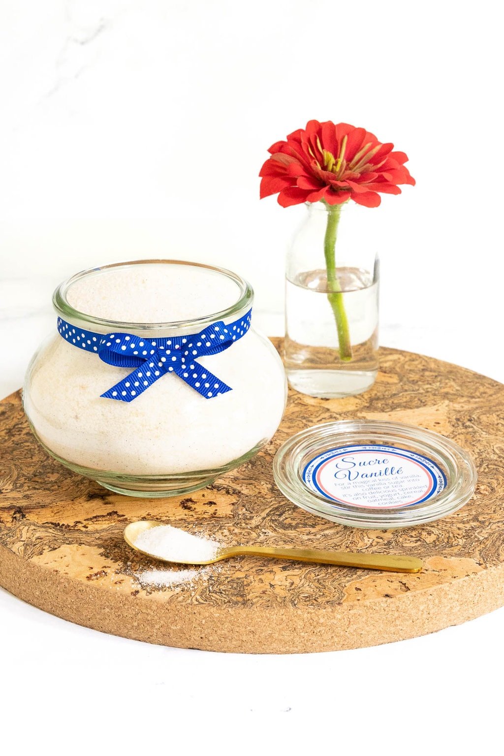 Vertical photo of French Vanilla Sugar (Sucre Vanillé) in a large glass Weck jar with a blue ribbon.