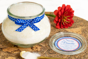 French vanilla sugar in a glass jar with a blue polka dot ribbon and custom label perfect for gifting.