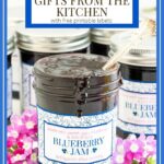 Vertical closeup photo of jars of Blueberry Freezer Jam surrounded by fresh flowers.