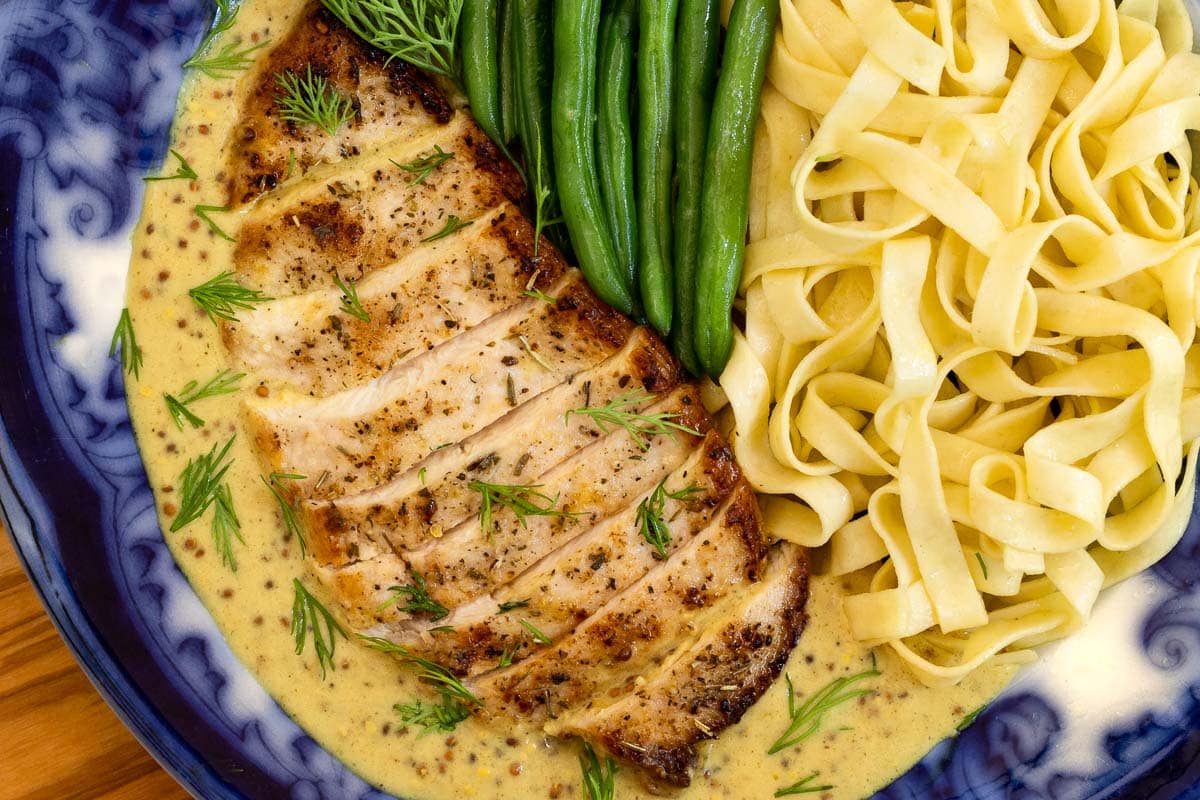 Horizontal overhead closeup photo of French Mustard Chicken Breasts (Poulet à la Moutarde Française) with pasta noodles and French green beans.