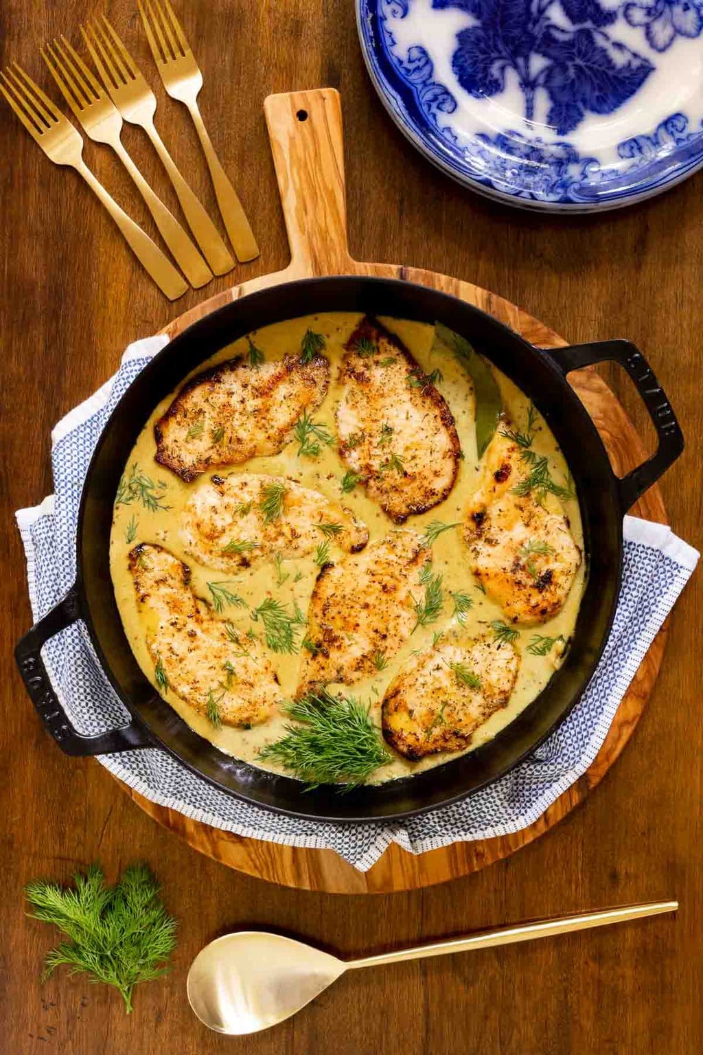 Vertical overhead photo of a black cast iron skillet with French Mustard Chicken Breasts (Poulet à la Moutarde Française) on a wood table.