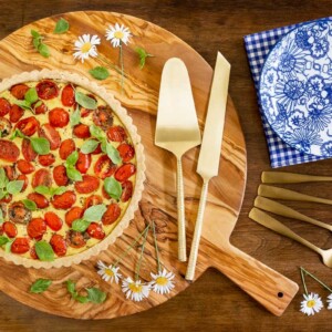Horizontal overhead photo of a French Tomato Ricotta Tart on a round wood cutting board.