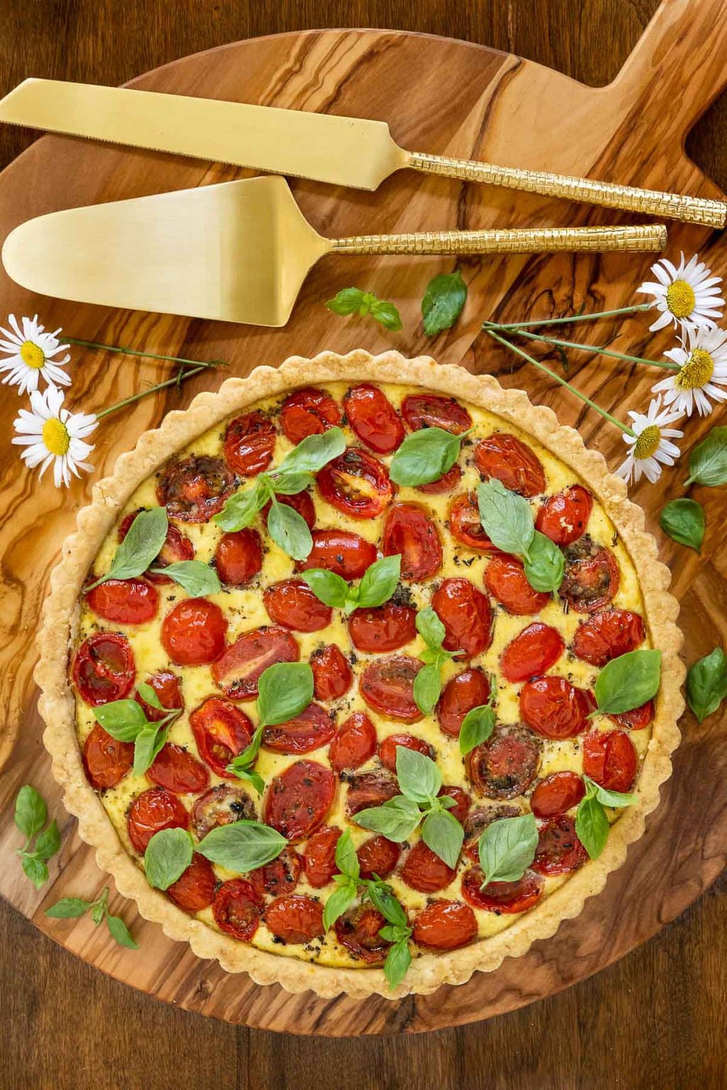 Vertical overhead photo of a French Tomato Ricotta Tart on a round wood cutting board.