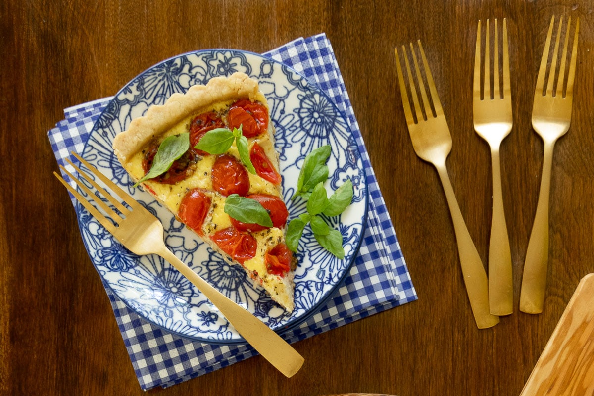 Horizontal overhead photo of a slice of French Tomato Ricotta Tart on a blue and white serving plate.